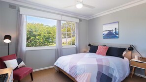 A bedroom with a large bed, a desk, a chair, a nightstand, and a ceiling fan. - Little Beach House, 4 James Crescent - Little Beach with air con, WiFi and boat parking (Nelson Bay)