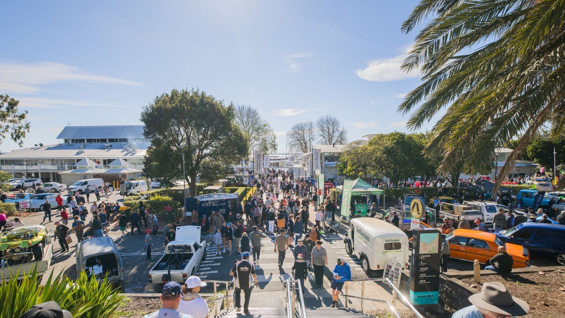 A busy outdoor event with people, vehicles, and tents.