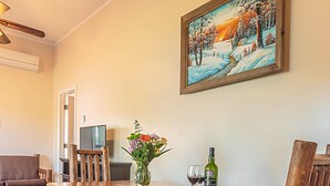 A dining area with a wooden table, benches, and chairs. A painting of a snowy landscape hangs on the wall. - Newly Renovated, Waterfront Cottages located in Prince Edward County (Milford)