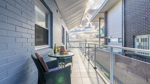 Un balcon avec une table, des chaises et une bouteille de vin.