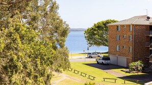 A residential building with a brick facade, a garage, and a view of a body of water. - Mistral Court, 14/17 Mistral Close - across the road from the beach (Nelson Bay)