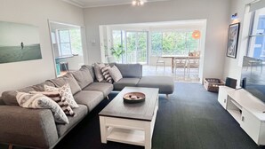 Un salon moderne avec un canapé gris, une table basse blanche et un téléviseur posé sur un meuble blanc.
