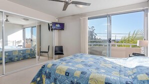 A hotel room with a large bed, a TV, a chair, and a balcony with a view. - Bayview Apartments, 11,42 Stockton Street - Three bedroom unit In the heart of town with air con, lift and secure parking (Nelson Bay)