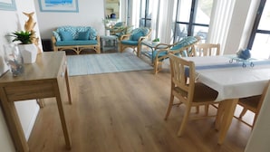 A spacious living area with a wooden floor, a dining table with chairs, a sofa, and a coffee table. - The Point, 5, 5-7 Mitchell Street large balcony with great water views (Soldiers Point)