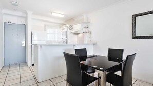 A compact kitchen with white cabinets, a built-in oven, and a clock on the wall. - Nelson Towers, 9,71a Victoria Parade - unit in the heart of Nelson Bay with water views, air conditioning and Wi-Fi (Nelson Bay)