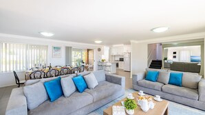 A modern living room with grey sofas, a coffee table, and a dining area with a table set for four.