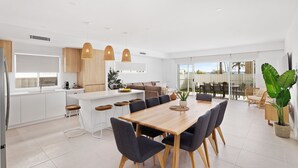 A modern kitchen with white cabinets, a central island, and pendant lighting. - Hideaway 1, 3 Lillian St -  stunning water views (Shoal Bay)