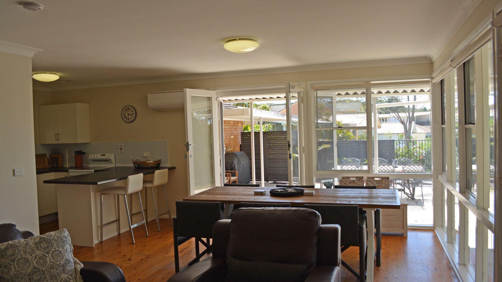 A compact kitchen with a dining area, a living room, and a sliding glass door leading to a patio.
