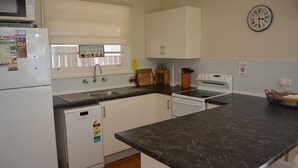 Una cocina con armarios blancos, un lavamanos, una estufa y un reloj en la pared.
