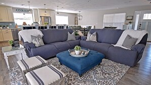 Ein modernes Wohnzimmer mit einem Ecksofa, einem Couchtisch und einem Essbereich im Hintergrund.