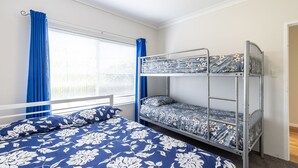A bunk bed room with a window, curtains, and floral bedding.