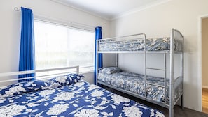 A bunk bed room with a window, curtains, and floral bedding.