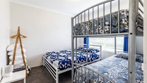 A bunk bed room with a floral bedspread, a wooden hanger, and a white lamp on a bedside table. - Adriana, 4/83 Ronald Avenue - open plan living with backyard (Shoal Bay)