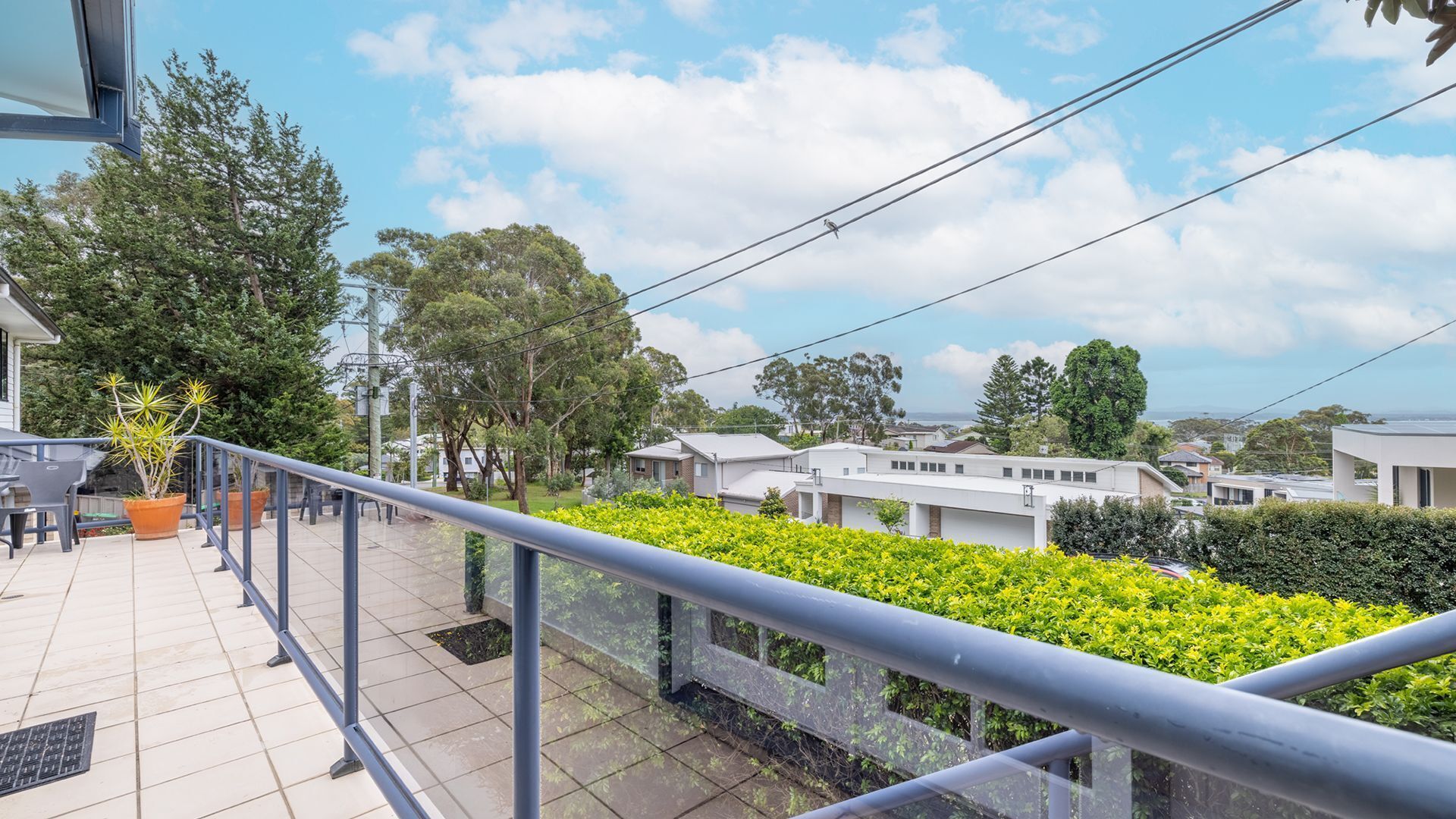A balcony with a view of residential buildings, a metal railing, and potted plants.