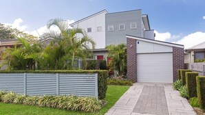A modern two-story house with a grey exterior, a brick section on the side, and a driveway leading to a garage. - 7 Judith Street - Stunning duplex with ducted air (Corlette)