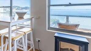 Une pièce comprenant une table et des chaises, une fenêtre donnant sur un plan d’eau et un appareil de climatisation.