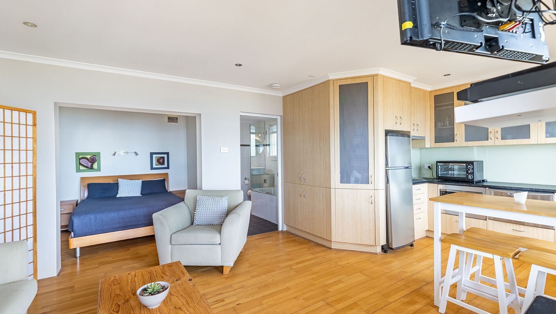 A modern apartment with a bedroom, living area, kitchenette, and a dining space.