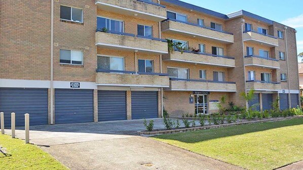 A multi-story apartment building with a brick facade, multiple balconies, and a ground-level commercial space.