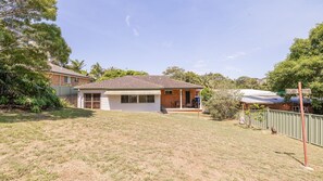 A single-story house with a tiled roof, a front porch, and a small backyard.
