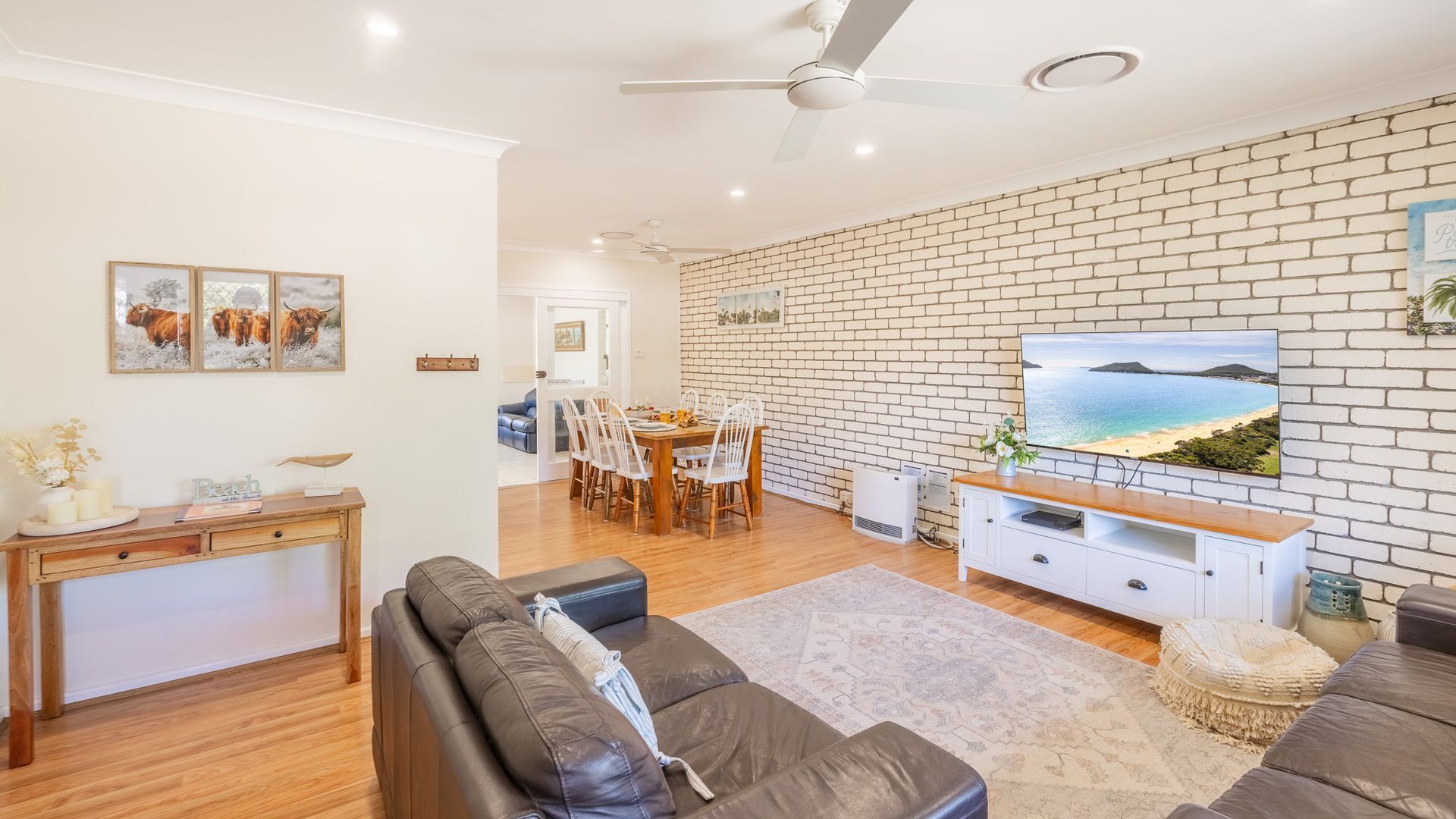 A living room with a brick wall, a television, and a dining area with chairs and a table.