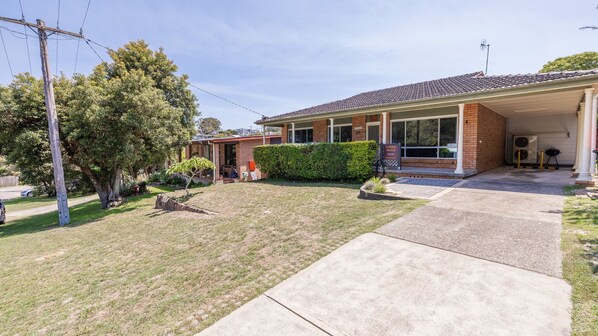 A two-story house with a covered porch, a brick exterior, and a well-maintained lawn.