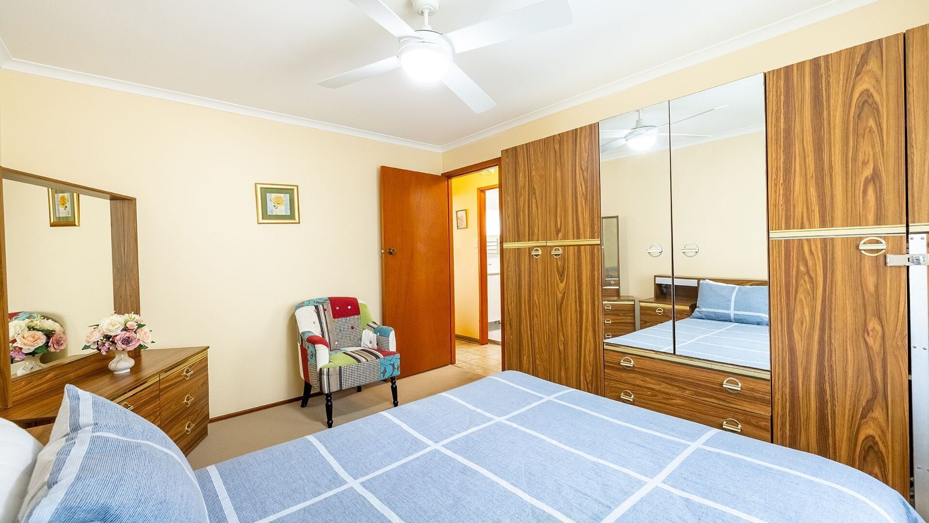 Un dormitorio con cama, cómoda, espejo y una silla.
