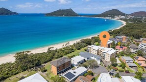 Une zone résidentielle côtière dotée d’une plage, de maisons et d’un repère orange bien visible.