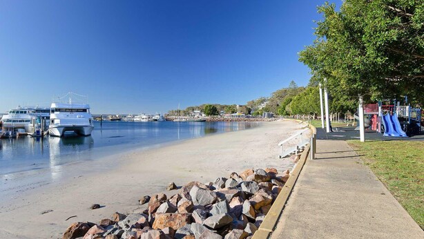 A beach with boats docked, a playground, and a clear sky.