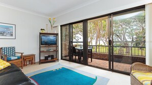 A living room with a TV, a bookshelf, a sofa, and a dining area with a table and chairs.
