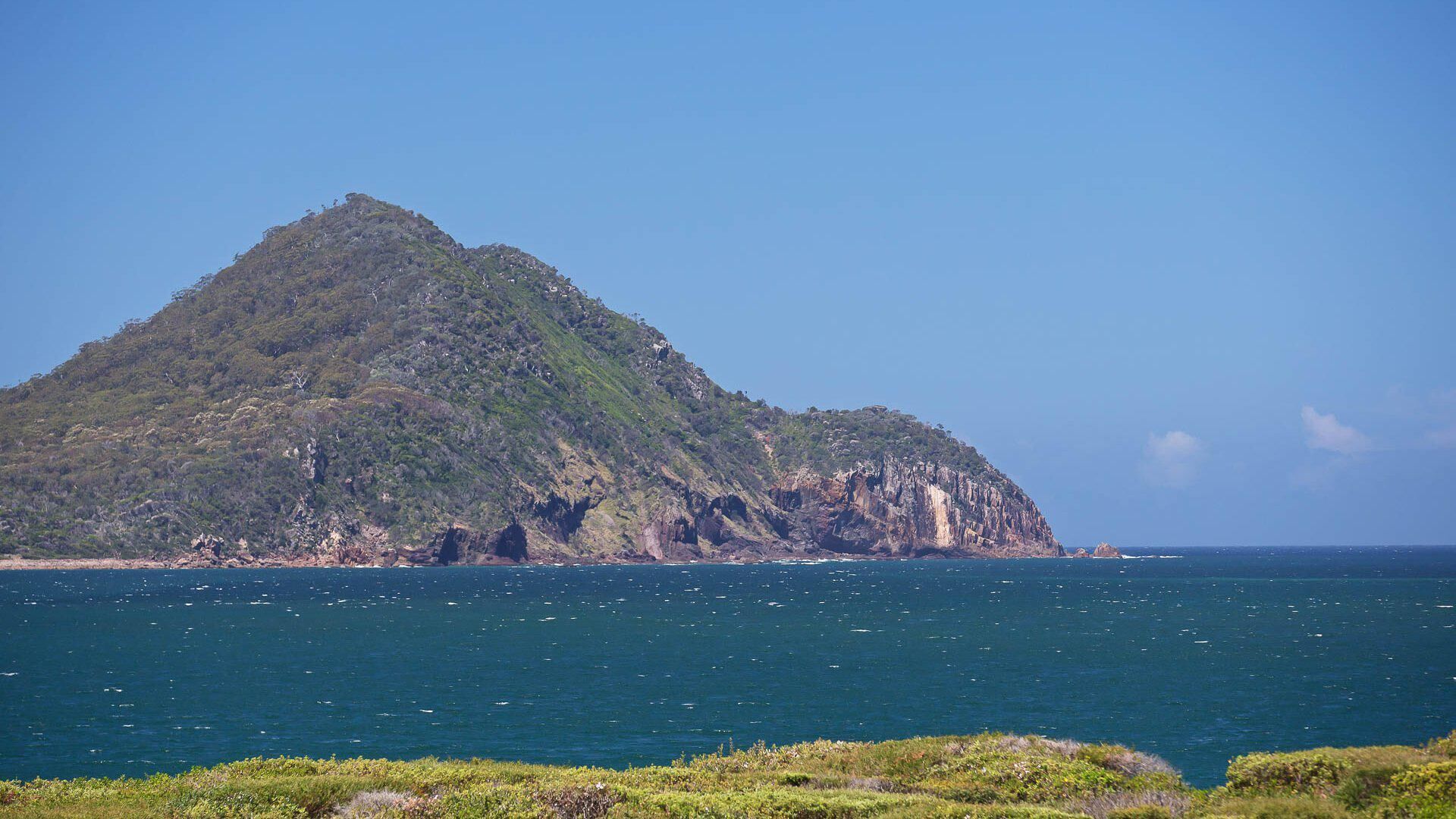 A coastal landscape with a prominent mountain and ocean.