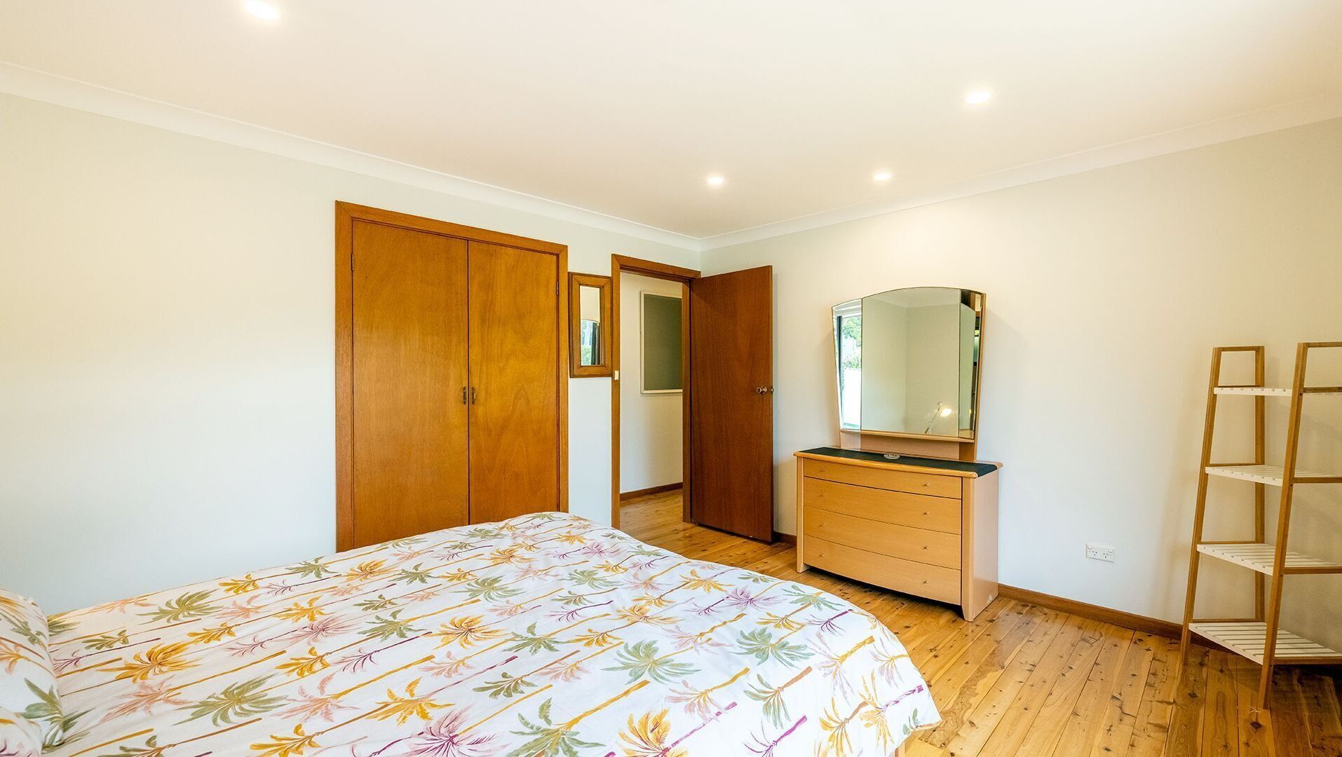 Ein Schlafzimmer mit Bett, Schminktisch, Spiegel und Holzschrank.