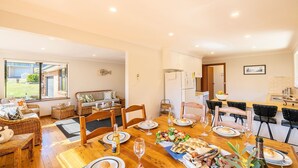 A dining area with a wooden table set for a meal, surrounded by wicker furniture and chairs.