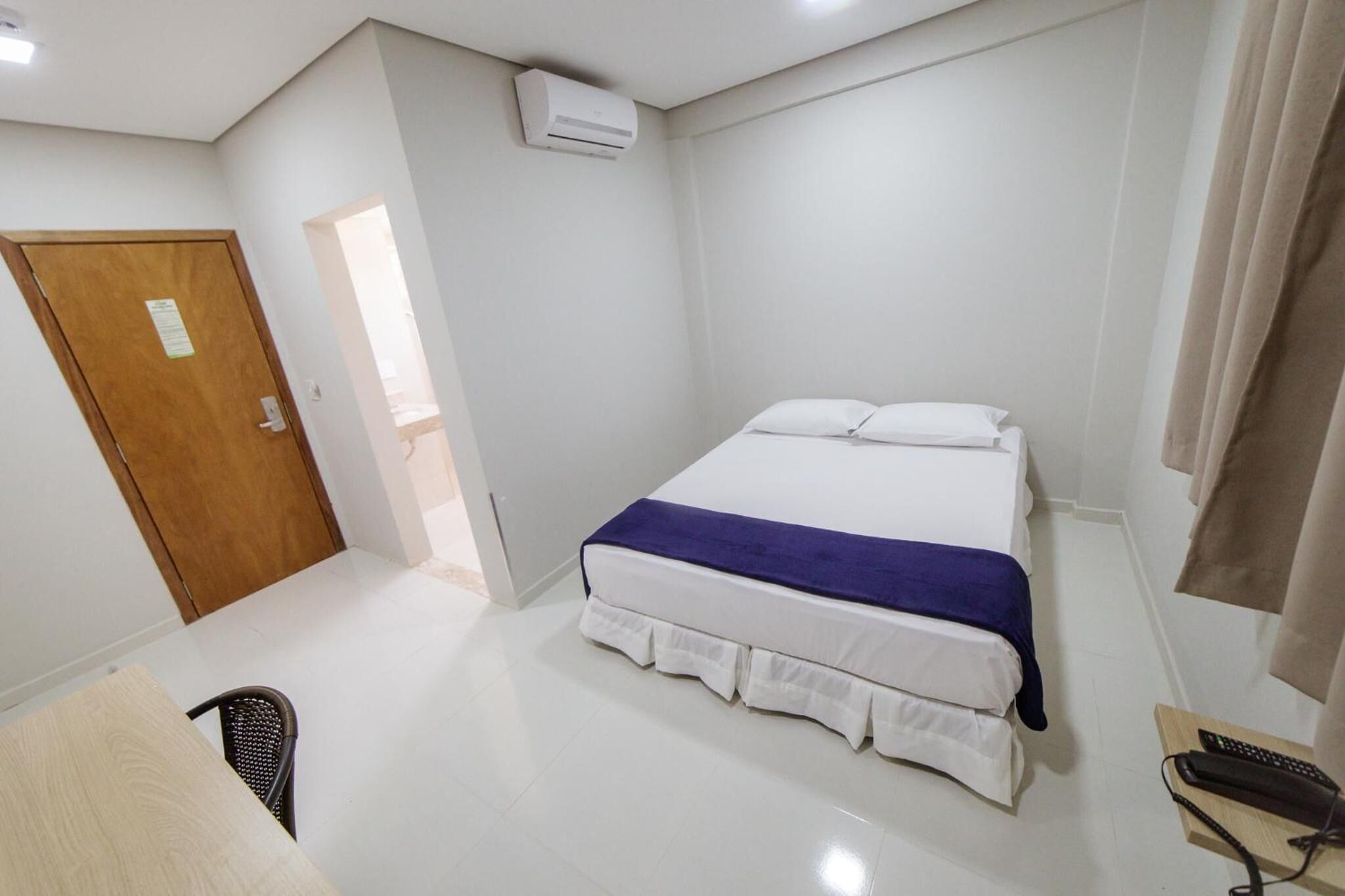Een slaapkamer met een bed, een bureau en een stoel.