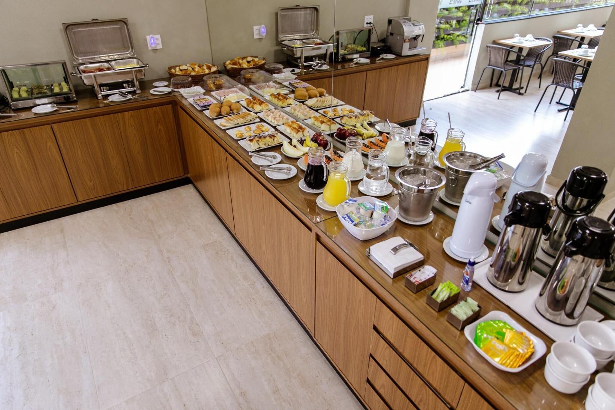A buffet with various food items and beverages, a coffee station, and a seating area with tables and chairs.