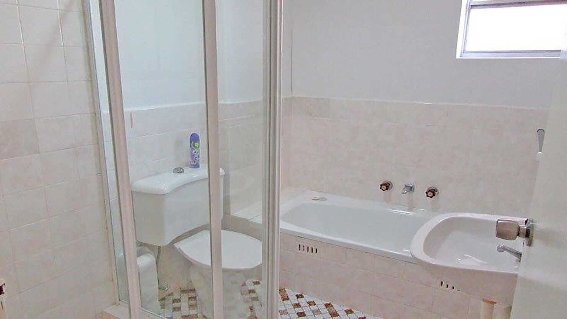 A bathroom with a bathtub, toilet, and shower area.