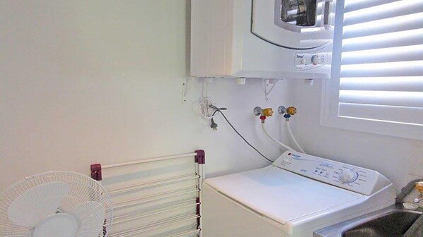 A laundry room with a dryer, a fan, and a microwave above the dryer. - Parkview, 10/11-13 Catalina Close - peaceful park views (Nelson Bay)