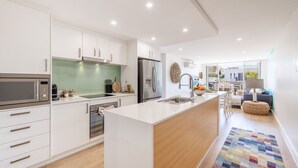 Uma cozinha moderna com armários brancos, eletrodomésticos de aço inoxidável e uma ilha central com pia.
