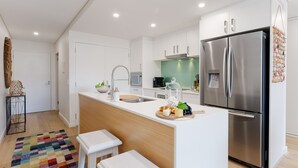 Une cuisine moderne dotée d’un îlot central, d’appareils électroménagers en acier inoxydable et d’un tapis aux couleurs vives.