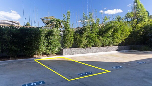 Uma área de estacionamento com vagas demarcadas, incluindo os números 102, 104 e 103.