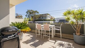 An outdoor patio with a barbecue grill, a table, and chairs.