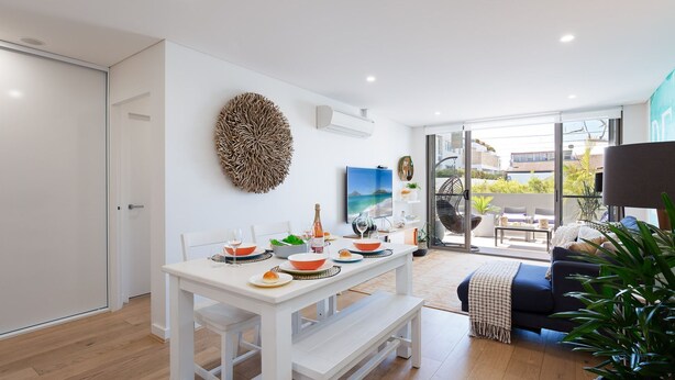 Un salon moderne comprenant un coin repas, un grand élément décoratif mural et une vue sur l’extérieur.