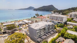 A coastal urban area with modern buildings, a beach, and a mountain in the background.