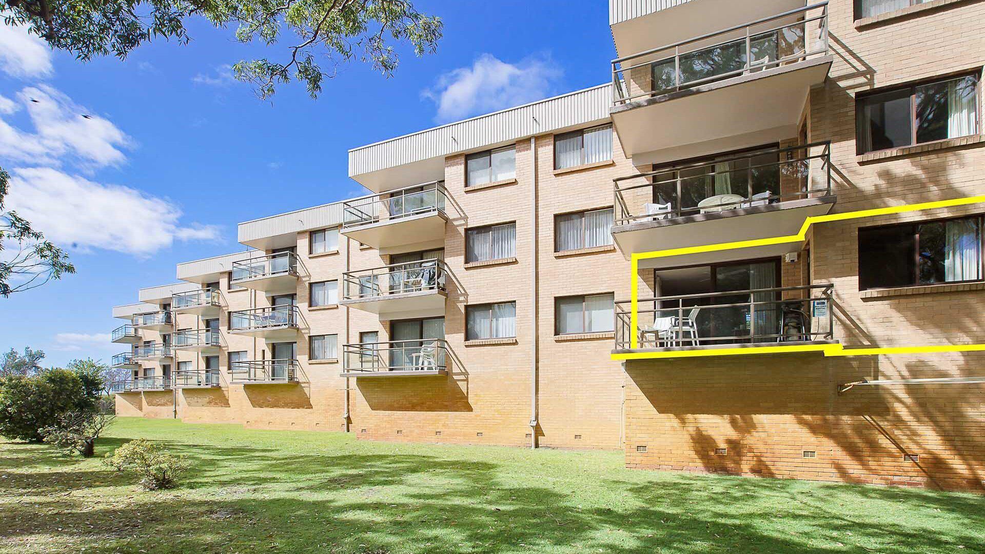 Un edificio residenziale a più piani con balconi, tetto piano e facciata in mattoni.