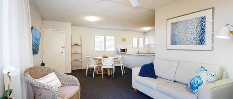 A compact living space with a dining area, kitchenette, and a sofa.