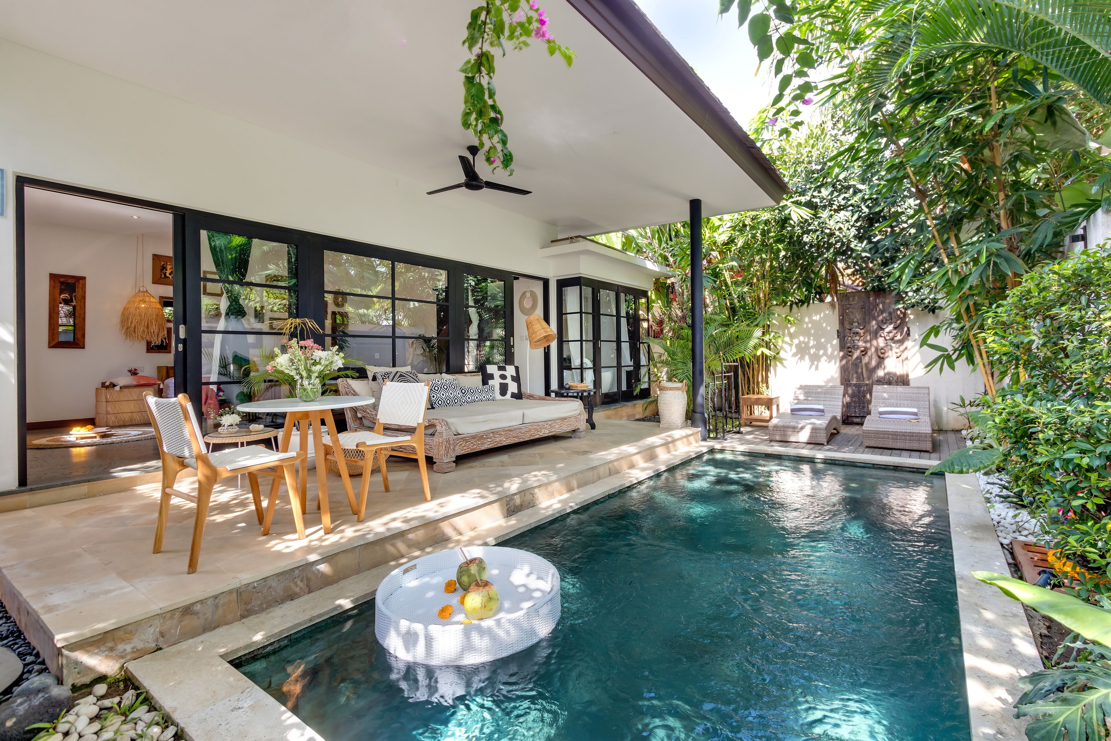 A poolside area with a seating arrangement, a ceiling fan, and a water feature.