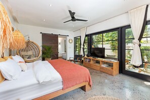 A modern bedroom with a bed, a ceiling fan, a TV, and large windows. - Villa Lora by Villa Finder (Ubud)