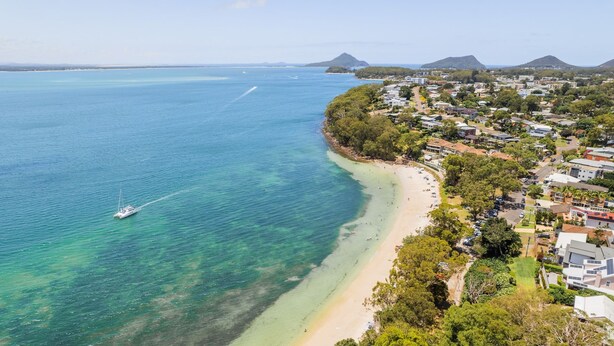 A coastal town with a beach, clear waters, and a yacht.