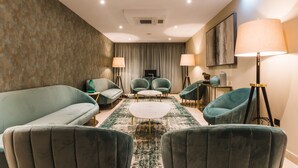 Ein modernes Wohnzimmer mit einer Couch, zwei Sesseln, einem Couchtisch und einer Stehlampe.