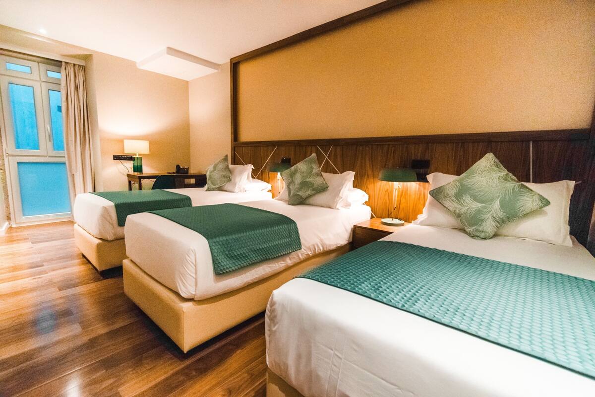 Une chambre d’hôtel avec deux lits, un bureau et une fenêtre.