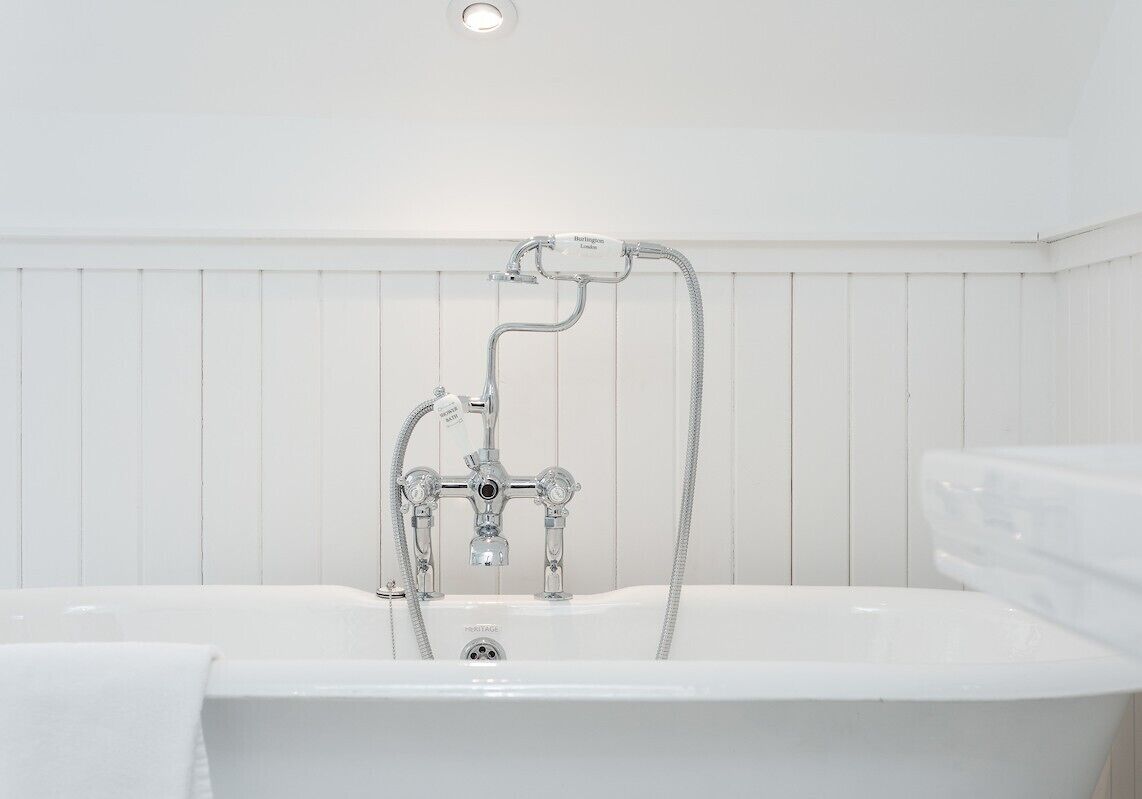 A white bathtub with a handheld showerhead and a built-in faucet.